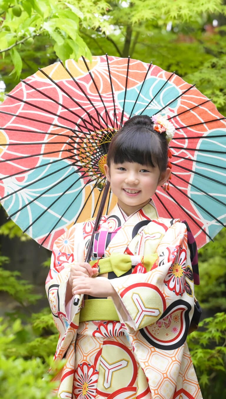 白地の着物に緑の帯揚げが映える、和傘を持った女の子